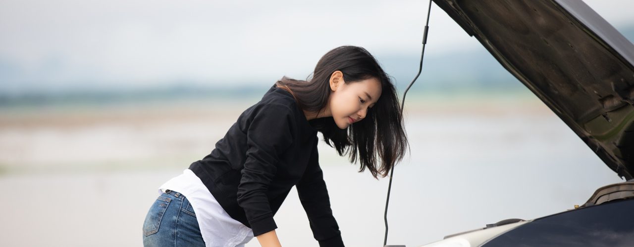 Young Girl Under Hood Of Broken Down Car Needing Roadside Assistance