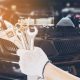 Person with glove holding wrenches for car maintenance