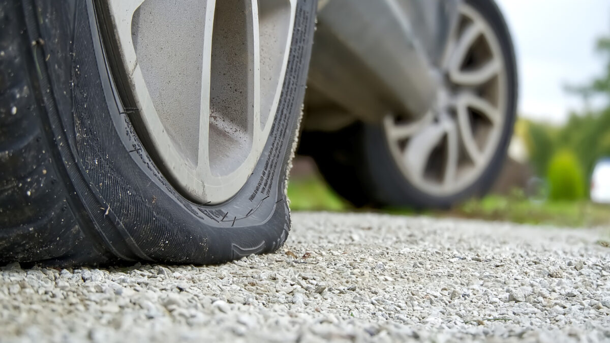 Close Up of a flat rear right tire on a car by side of road