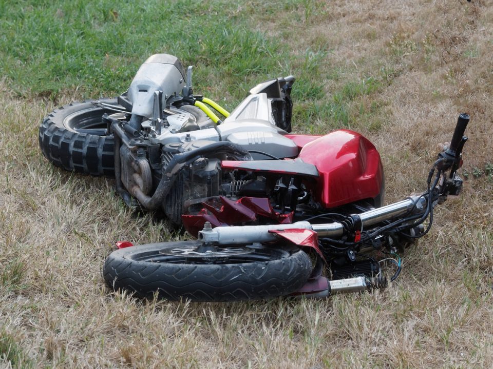 Motorcycle broken and wrecked on grass because of an accident.